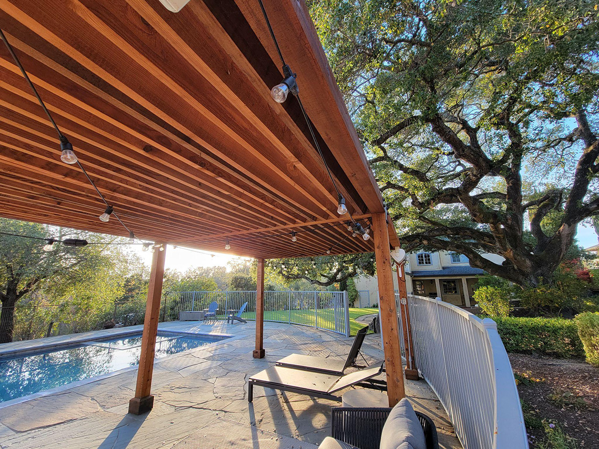 large wooden frame with lights over patio space with chairs