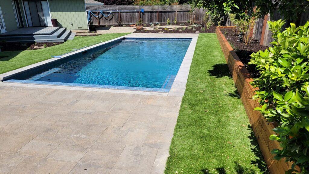 backyard with pool, green grass and plants