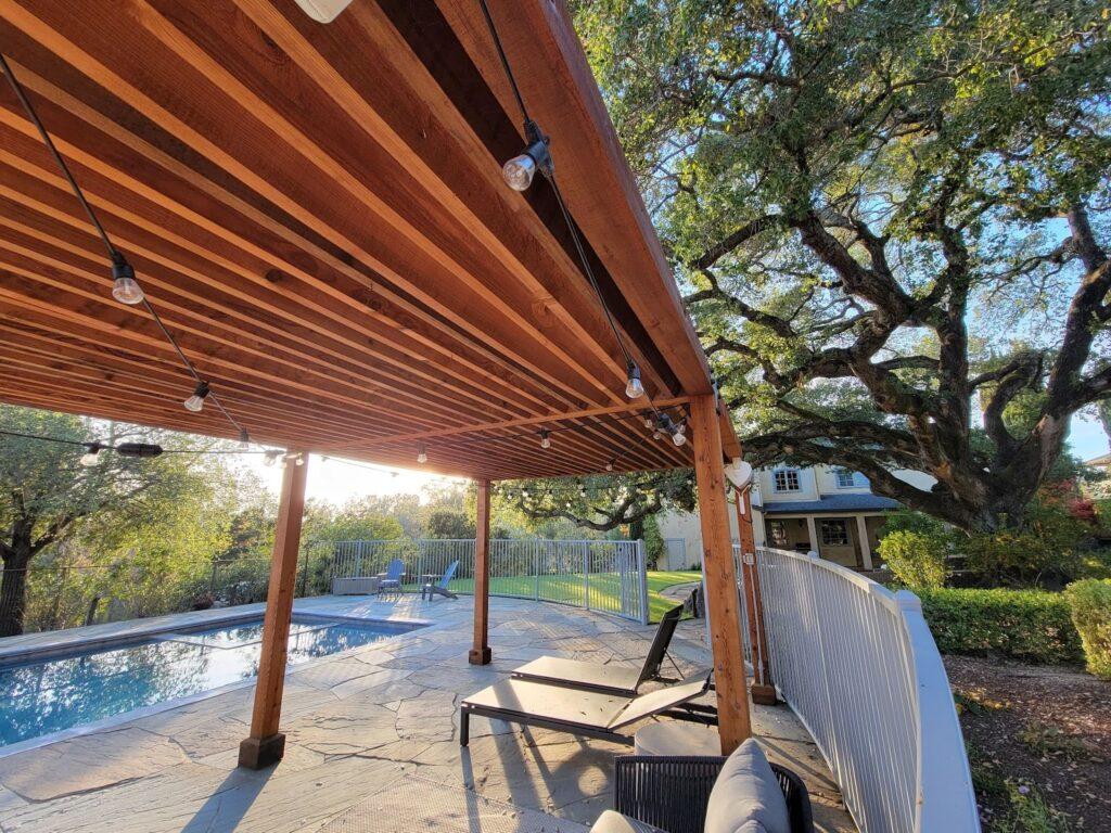 large wooden frame with lights over patio space with chairs