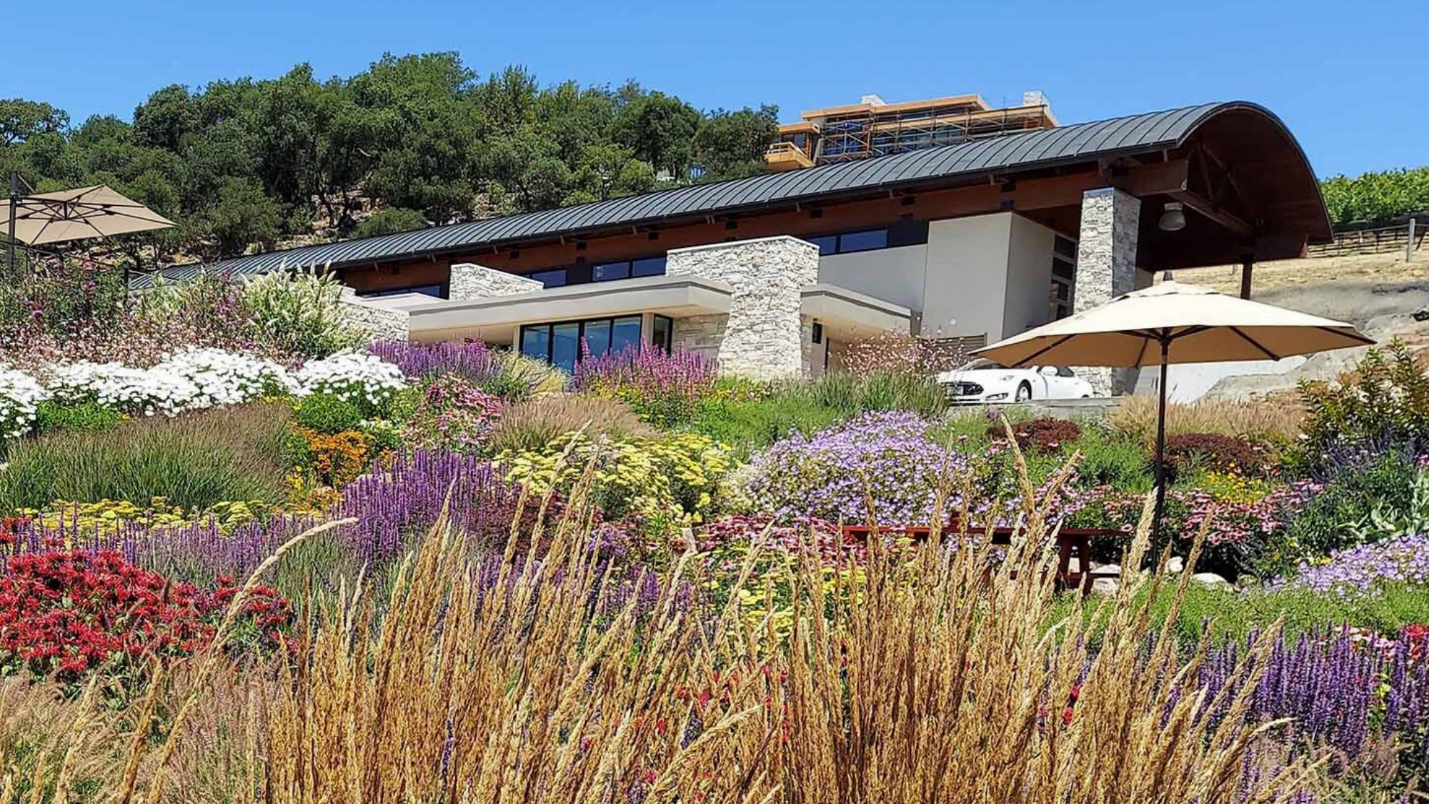 A modern home with a lush colorful landscape of many different flowers and bushes.