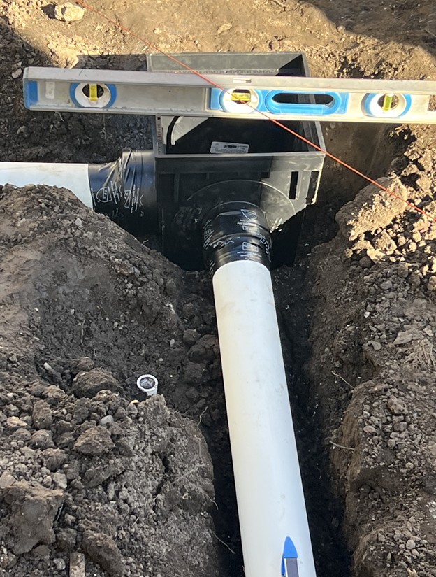 A construction worker is seen installing a pipe underground, preparing for essential infrastructure development.