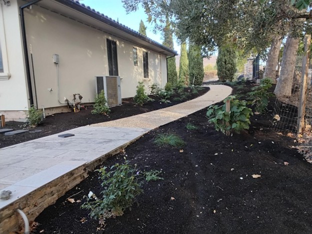 A crushed rock pathway on a low traffic side of the house transitioning to a paved patio in the back entertainment areas that get more frequent use in Calistoga.