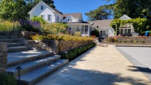 Hardscaping steps leading down to a pool area surrounded by colorful landscaping.