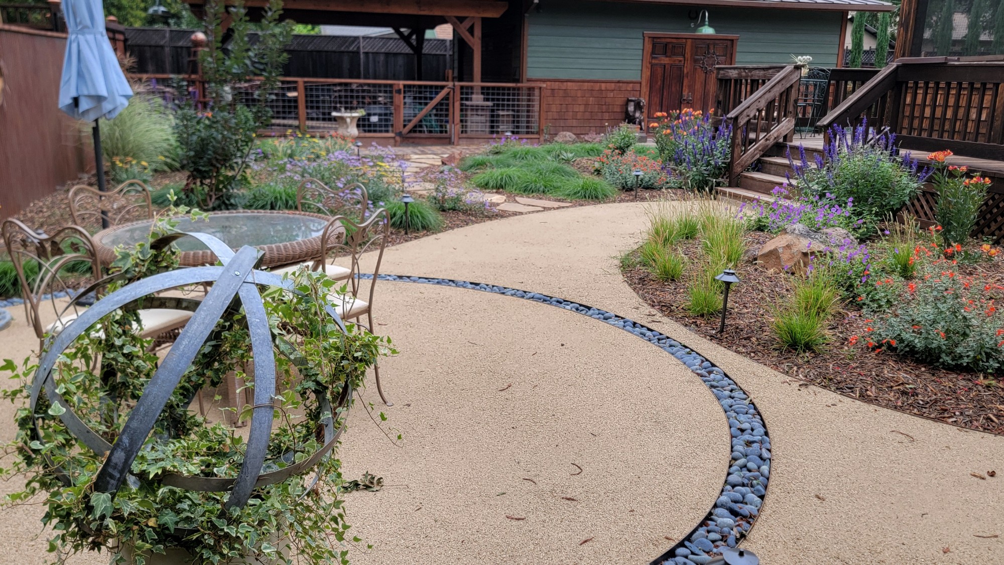A metal feature with lush vines growing on it in a fully landscaped backyard.