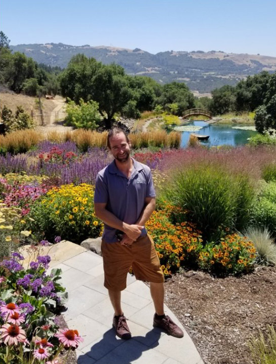 Man standing on paved garden path in summer garden.