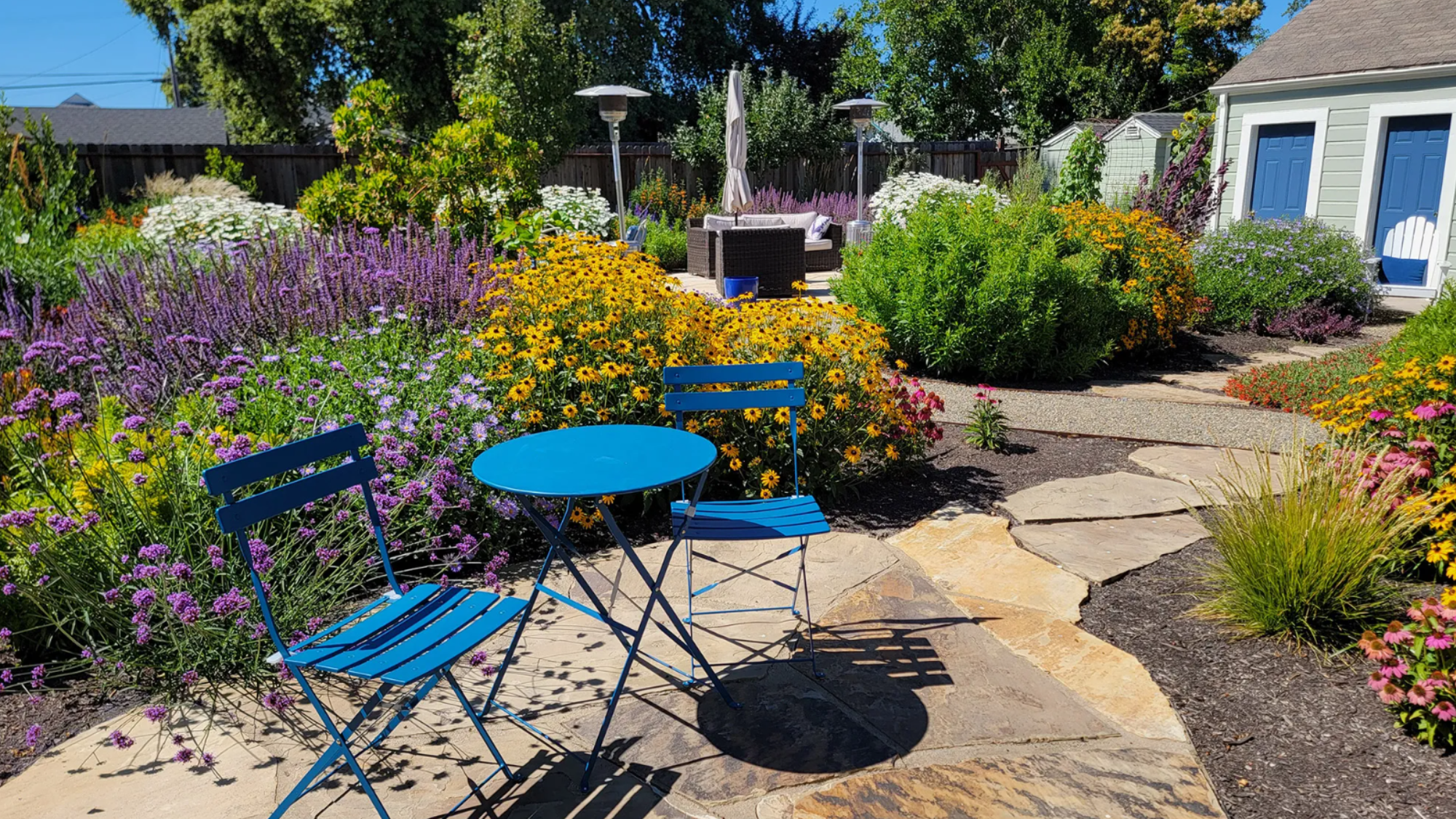 Bright blue chairs and table on the hardscaping of the Petaluma Pollinator Location.